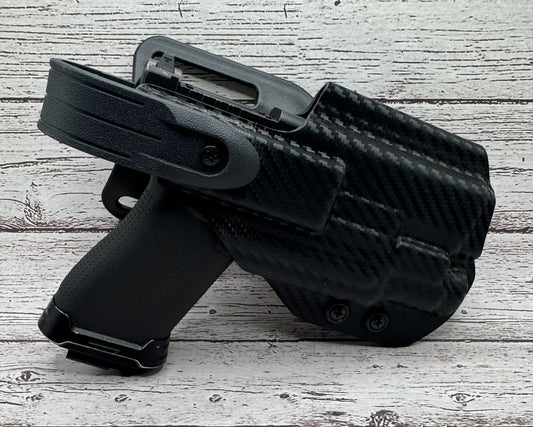 Black firearm holster on a textured light gray surface